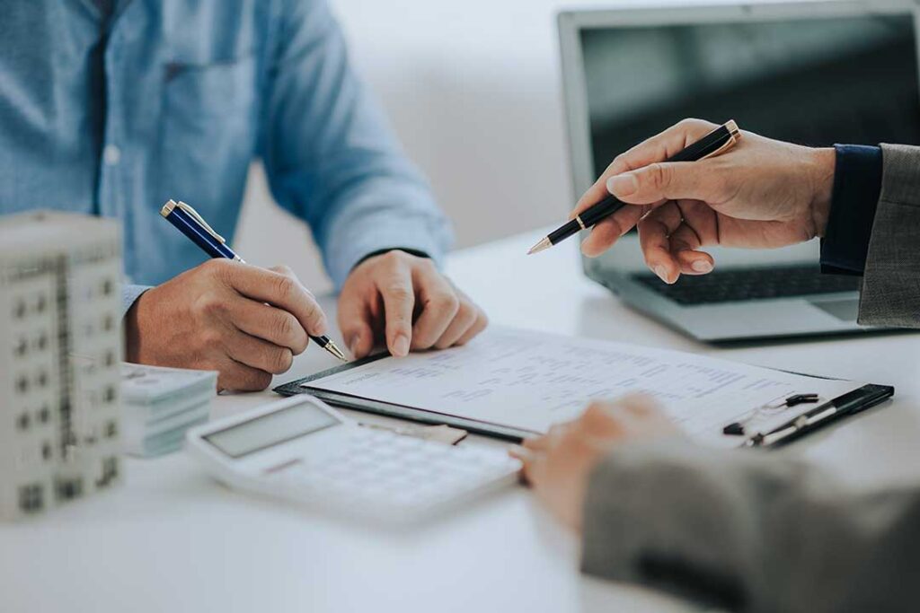 A family of three sits together at a kitchen table, reviewing documents and discussing their finances.